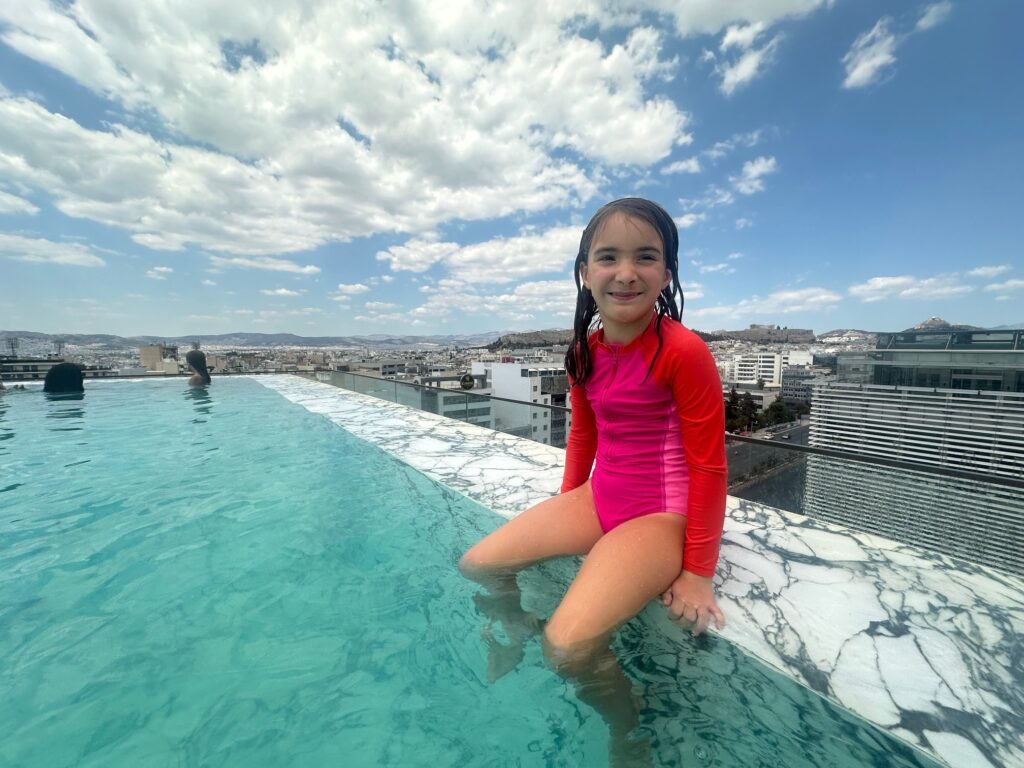 Child relaxing by the rooftop pool at Grand Hyatt Athens, enjoying a family-friendly Greek island hopping itinerary