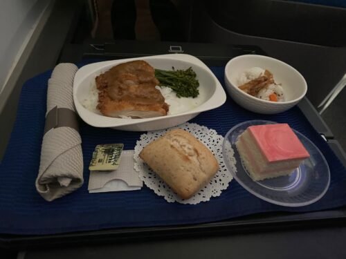 Meal service image for United Polaris 787 review, showing dinner with chicken, broccolini, salad, and guava cake in Polaris Business Class